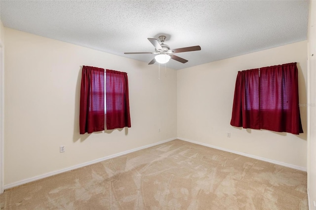 carpeted empty room featuring ceiling fan, a textured ceiling, and baseboards