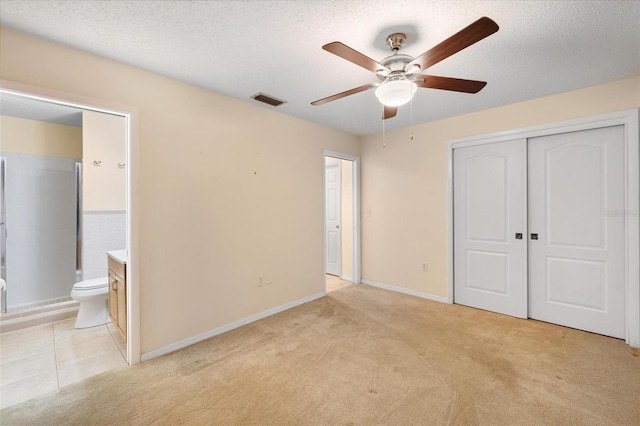 unfurnished bedroom with a textured ceiling, connected bathroom, visible vents, and light colored carpet