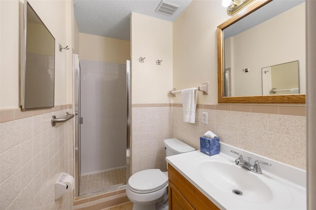 full bath featuring a textured ceiling, toilet, visible vents, tile walls, and a shower stall