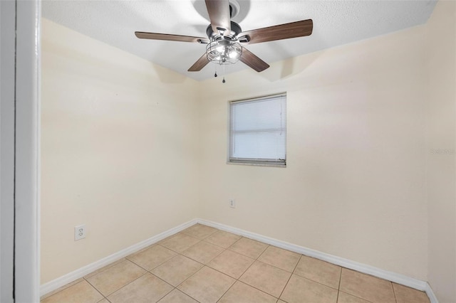 spare room featuring ceiling fan, a textured ceiling, baseboards, and light tile patterned floors