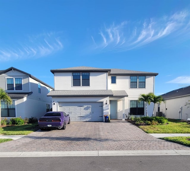 view of front facade featuring a garage, central AC unit, and decorative driveway