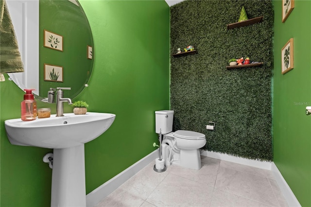 bathroom with tile patterned flooring, baseboards, a sink, and toilet