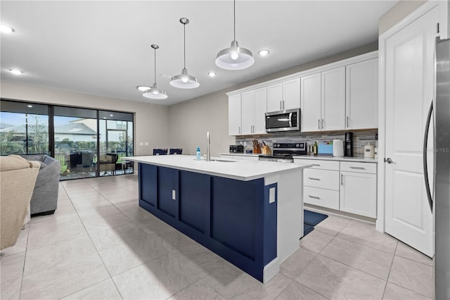 kitchen featuring stainless steel appliances, light countertops, open floor plan, white cabinetry, and a sink