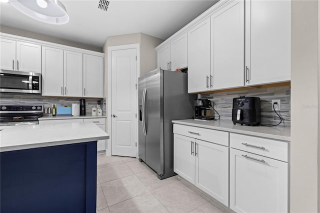 kitchen with light tile patterned flooring, visible vents, white cabinetry, appliances with stainless steel finishes, and decorative backsplash