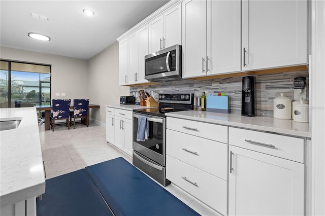 kitchen featuring light tile patterned floors, visible vents, white cabinetry, appliances with stainless steel finishes, and backsplash