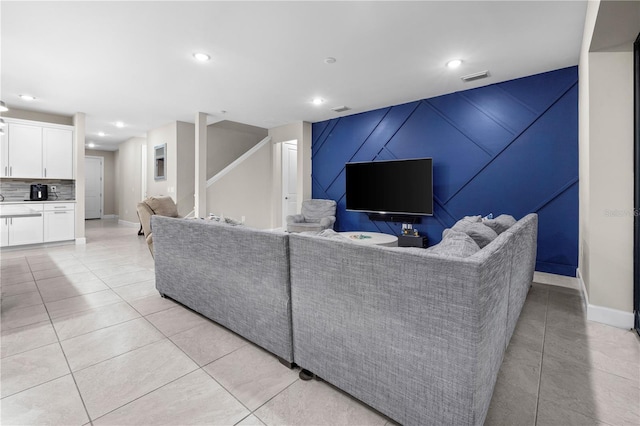 living area with light tile patterned floors, recessed lighting, an accent wall, visible vents, and stairway