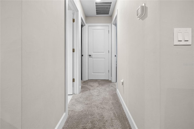 hallway with baseboards, visible vents, and carpet flooring