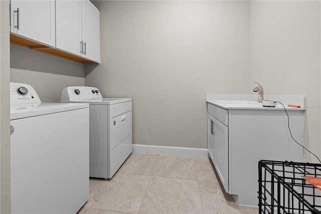 clothes washing area featuring cabinet space, baseboards, a sink, and washing machine and clothes dryer