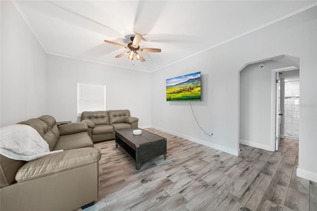 living room featuring baseboards, arched walkways, ceiling fan, wood finished floors, and crown molding