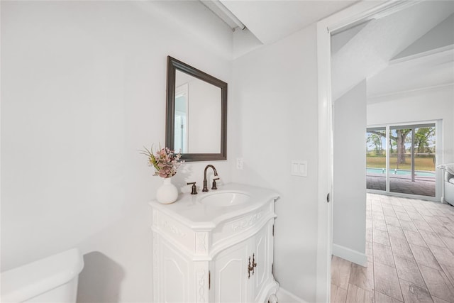 bathroom with toilet, baseboards, wood finished floors, and vanity