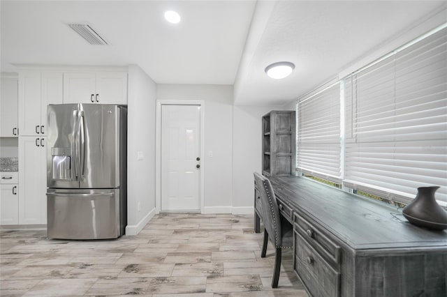 kitchen with visible vents, baseboards, white cabinets, light wood-type flooring, and stainless steel fridge