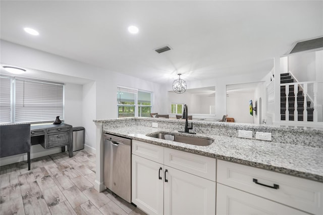 kitchen with visible vents, an inviting chandelier, stainless steel dishwasher, white cabinetry, and a sink