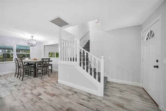 dining space with a notable chandelier, wood finished floors, visible vents, baseboards, and stairs