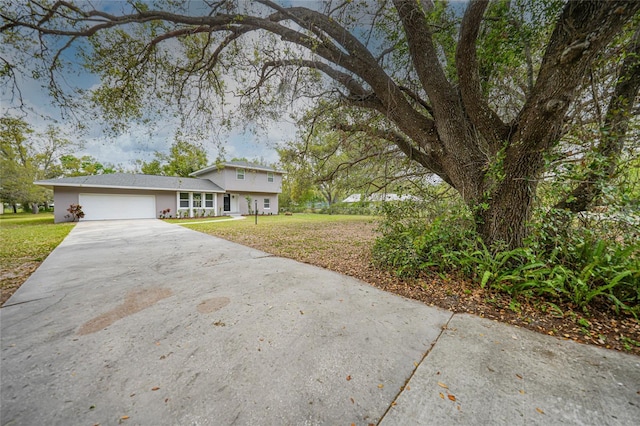 view of front of property featuring a front yard, concrete driveway, and an attached garage