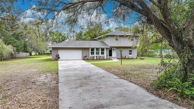 view of front of house with concrete driveway, a front lawn, an attached garage, and fence
