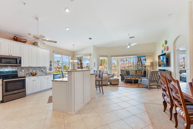 kitchen featuring light tile patterned flooring, open floor plan, backsplash, and appliances with stainless steel finishes