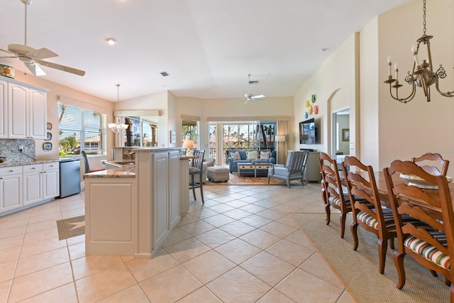 kitchen with light tile patterned floors, stainless steel dishwasher, decorative light fixtures, ceiling fan with notable chandelier, and backsplash