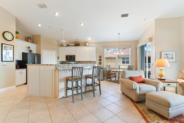 kitchen featuring light tile patterned flooring, stainless steel microwave, refrigerator with ice dispenser, and visible vents