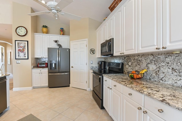 kitchen with light tile patterned floors, arched walkways, appliances with stainless steel finishes, and white cabinetry