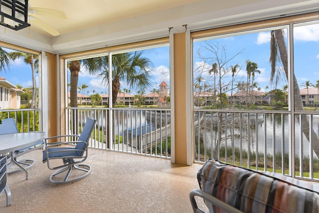 sunroom / solarium with a residential view, ceiling fan, and a water view