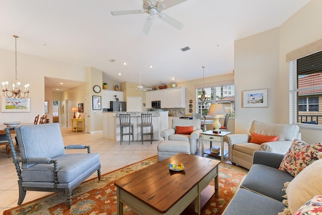 living area featuring visible vents, lofted ceiling, light tile patterned flooring, and ceiling fan with notable chandelier