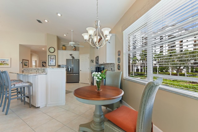 dining space featuring ceiling fan with notable chandelier, vaulted ceiling, light tile patterned floors, and recessed lighting