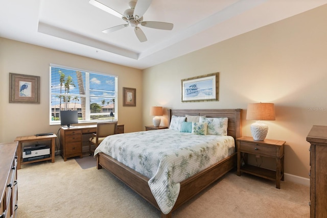 bedroom featuring a tray ceiling, baseboards, light colored carpet, and a ceiling fan