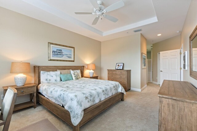 bedroom featuring visible vents, a raised ceiling, light colored carpet, and baseboards