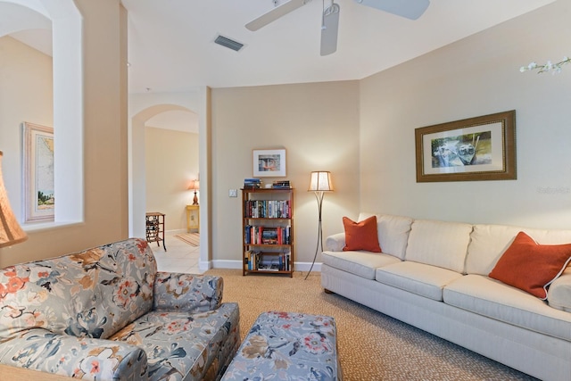 carpeted living room with visible vents, arched walkways, baseboards, and ceiling fan