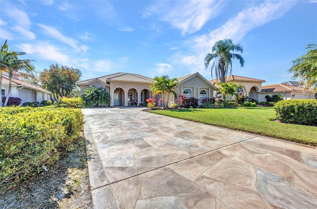 mediterranean / spanish-style house featuring driveway, a tiled roof, and a front yard