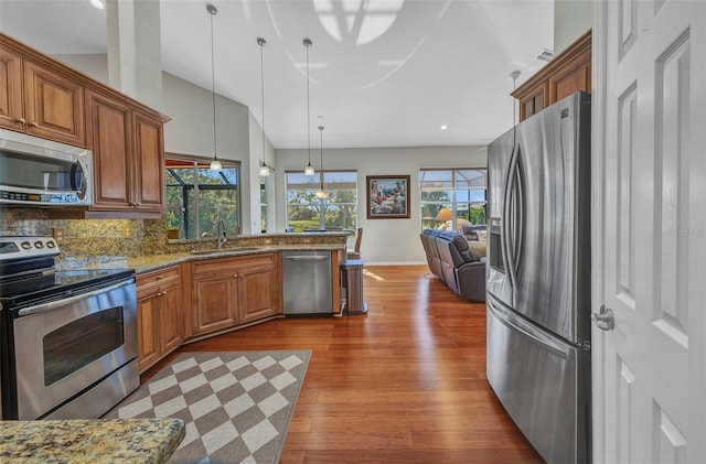 kitchen with stainless steel appliances, dark wood-type flooring, a sink, backsplash, and brown cabinets