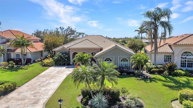 mediterranean / spanish home with driveway, a front yard, a tile roof, and stucco siding