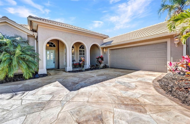 mediterranean / spanish home featuring a tile roof, driveway, an attached garage, and stucco siding