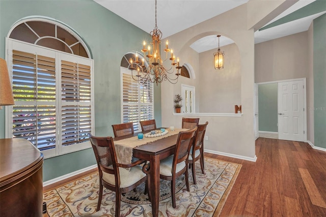 dining room with arched walkways, high vaulted ceiling, wood finished floors, and baseboards