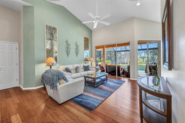 living area featuring high vaulted ceiling, a sunroom, baseboards, and wood finished floors