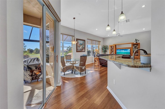 kitchen with stone counters, visible vents, pendant lighting, and wood finished floors