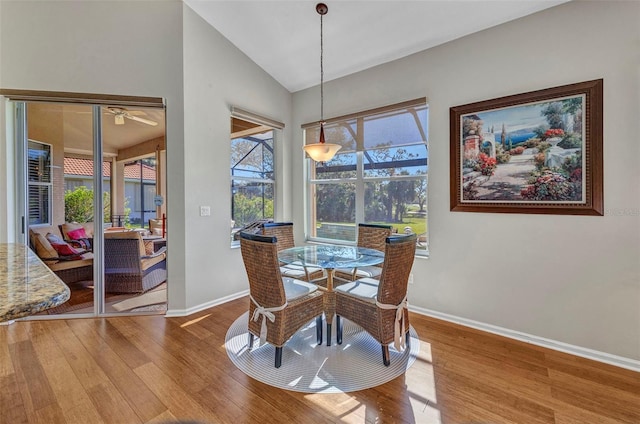 dining area with lofted ceiling, baseboards, and wood finished floors