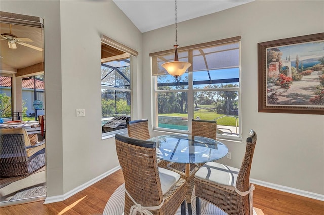 dining room with lofted ceiling, a sunroom, baseboards, and wood finished floors