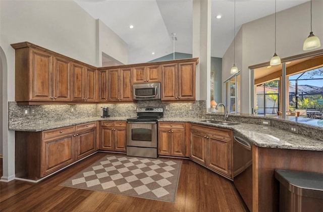 kitchen with brown cabinets, appliances with stainless steel finishes, a sink, and decorative backsplash