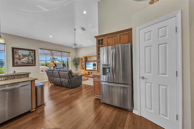 kitchen with light stone counters, dark wood-style floors, brown cabinets, visible vents, and appliances with stainless steel finishes