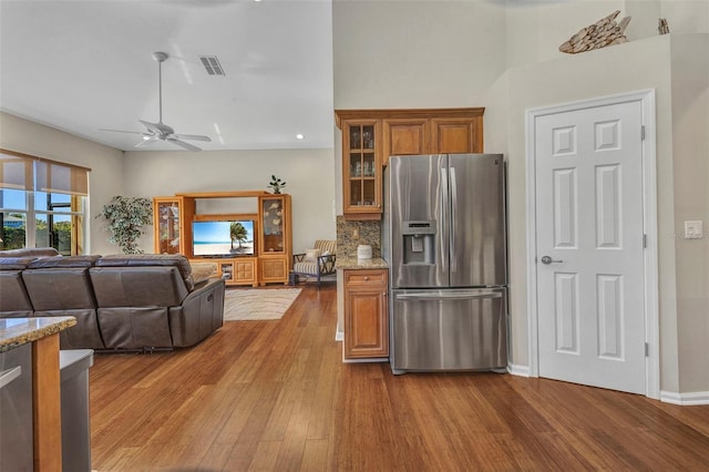 kitchen with stainless steel fridge, visible vents, decorative backsplash, brown cabinets, and wood finished floors