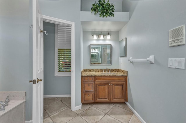 bathroom with tile patterned floors, baseboards, a tub, and vanity