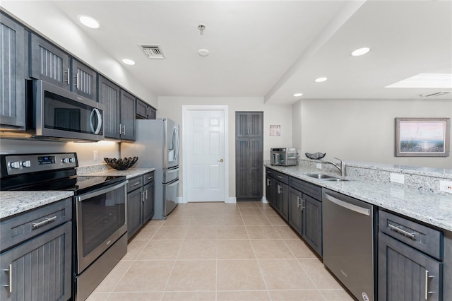 kitchen with light stone countertops, visible vents, light tile patterned flooring, a sink, and stainless steel appliances