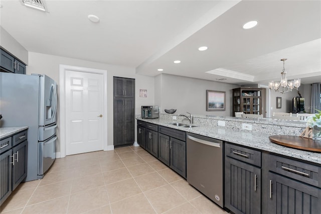 kitchen with a sink, light stone countertops, appliances with stainless steel finishes, and recessed lighting