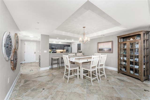 dining room with a raised ceiling, baseboards, and a chandelier