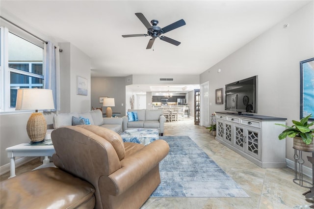 living room with ceiling fan with notable chandelier, visible vents, and baseboards