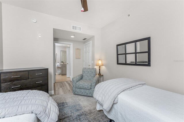 bedroom featuring a ceiling fan, ensuite bath, wood finished floors, and visible vents