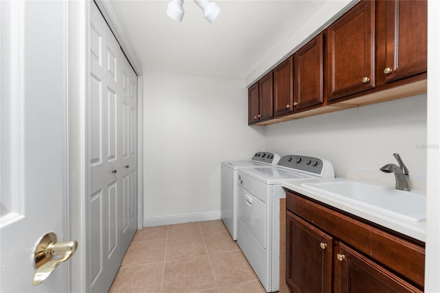 washroom featuring baseboards, light tile patterned flooring, cabinet space, independent washer and dryer, and a sink