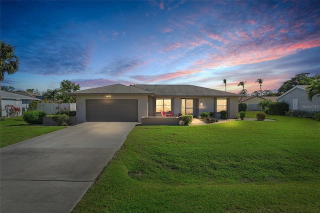 single story home featuring an attached garage, fence, a yard, concrete driveway, and stucco siding