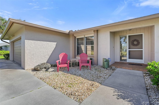 view of exterior entry featuring a garage, driveway, and stucco siding